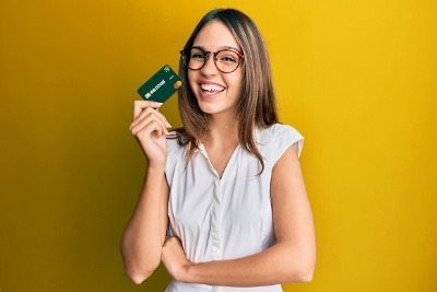 Girl with glasses smiling and holding a home state bank debit card
